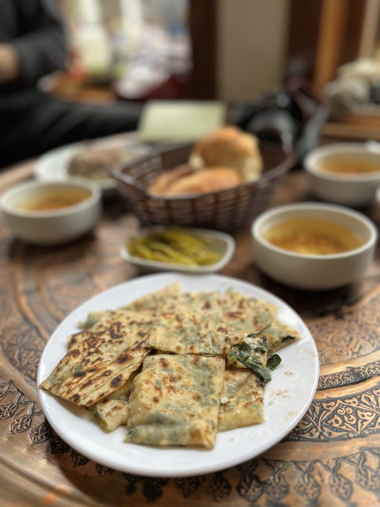 Hvid tallerken med små tilberedte fladbrød skåret i firkanter med krydderurter på