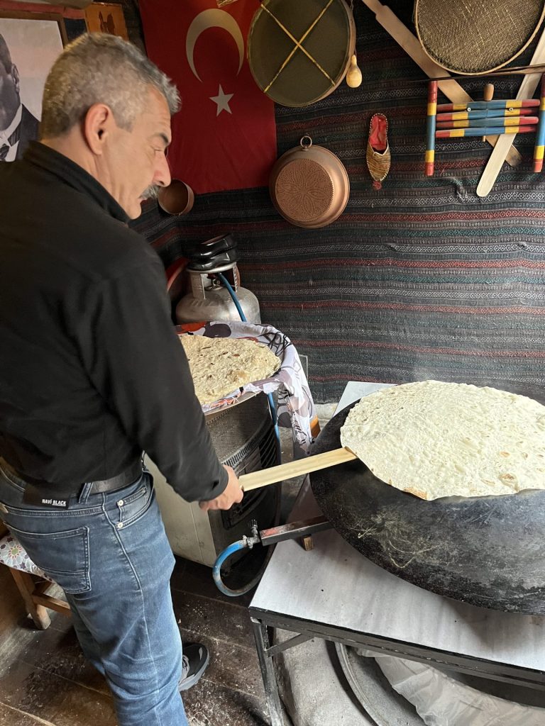 Mand tilbereder stort fladbrød på en stor rund sort pande