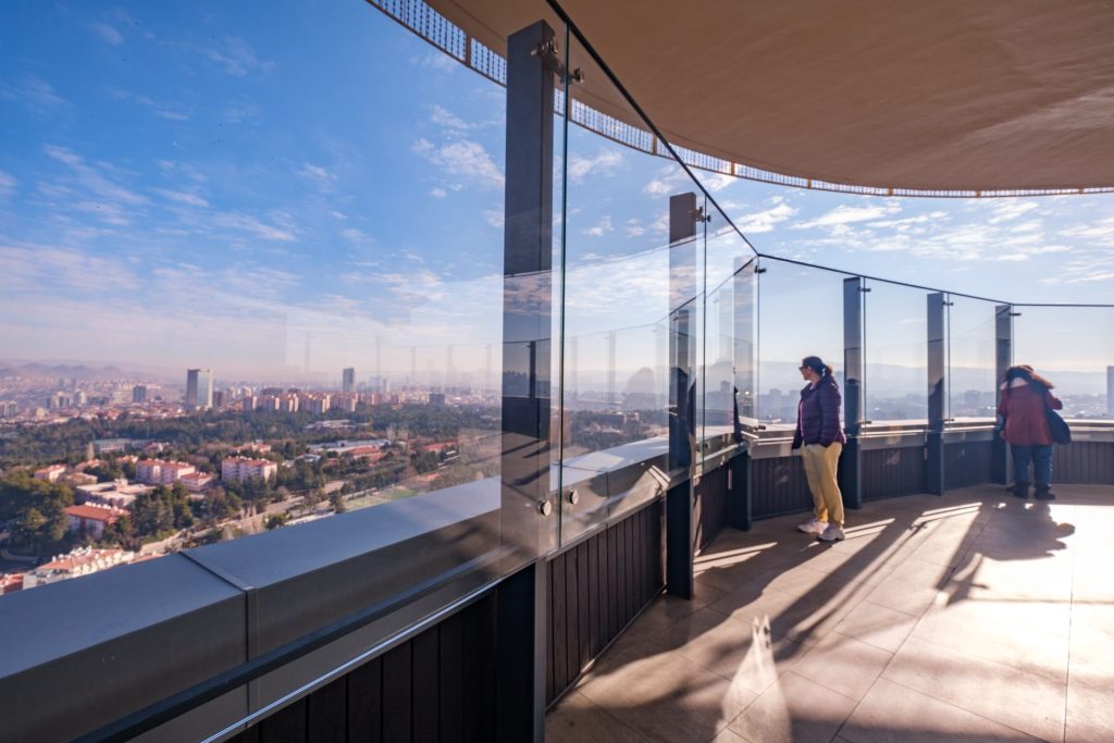 to personer står i et udsigtstårn med glasvægge med udsigt over by