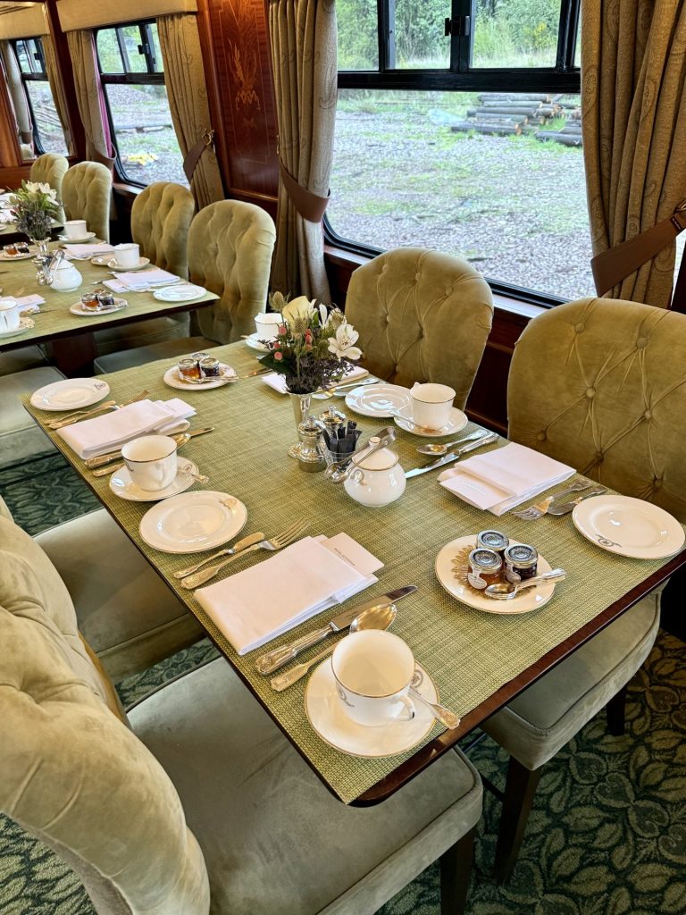 Flere firkantede spiseborde med grøn overflade dækket med tallerkener og service og grønne stole omkring