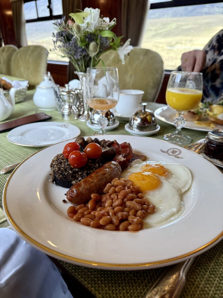 En hvid tallerken med klassisk engelsk morgenmad på bestående af æg, pølser og bønner