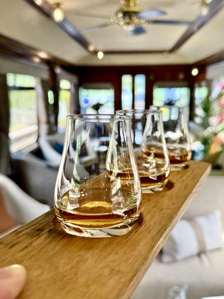 Tre whisky-glas med whisky i på et serveringsbræt i træ