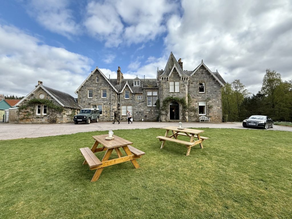 To bordebænkesæt på en græsplæne foran et stort, gråt hus