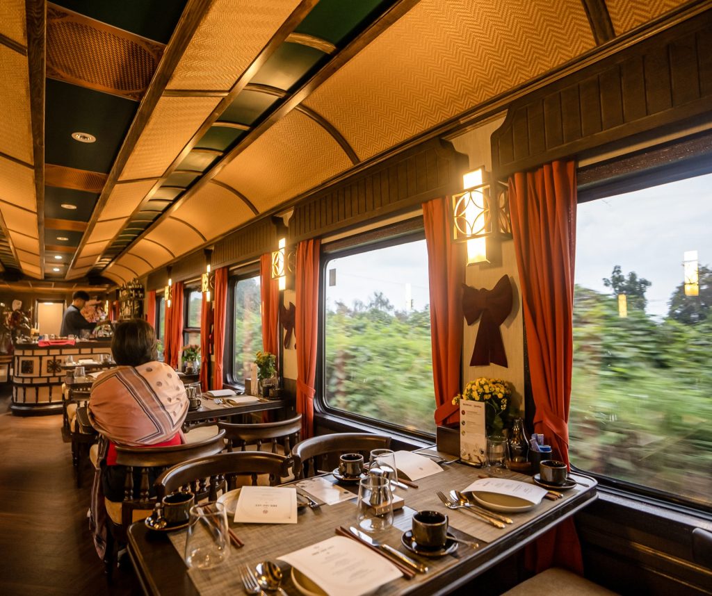 En person siddende i en togvogn med spisepladser og bar, der er i bevægelse