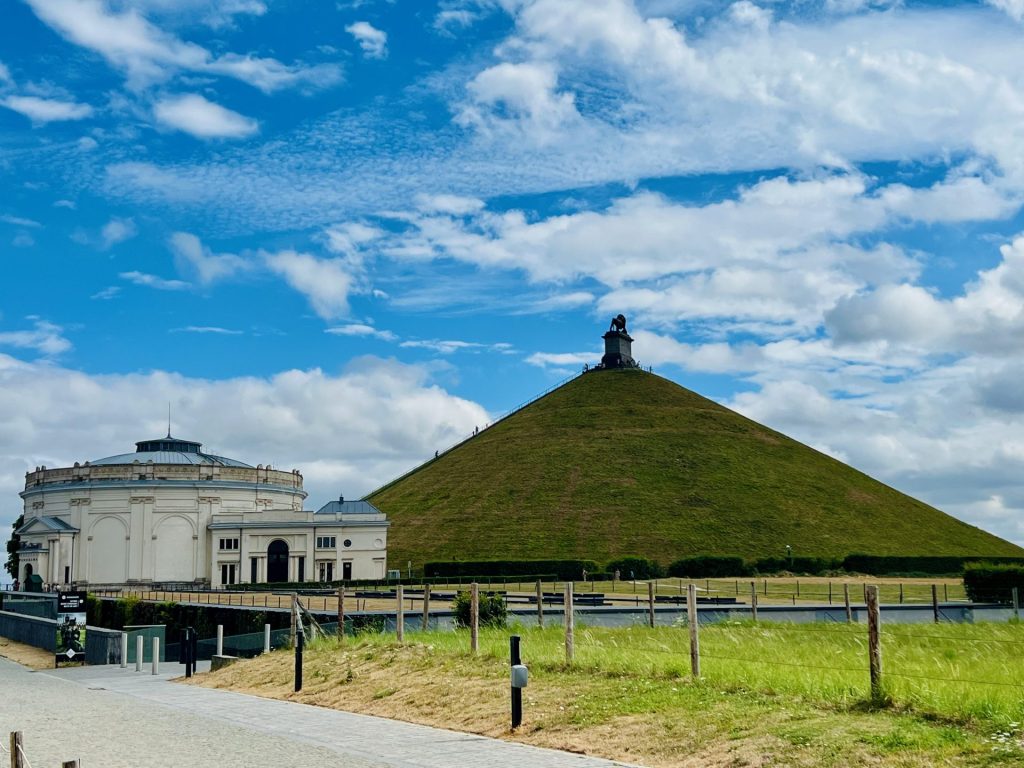 Kegleformet bakke og gammel bygning og blå himmel med skyer